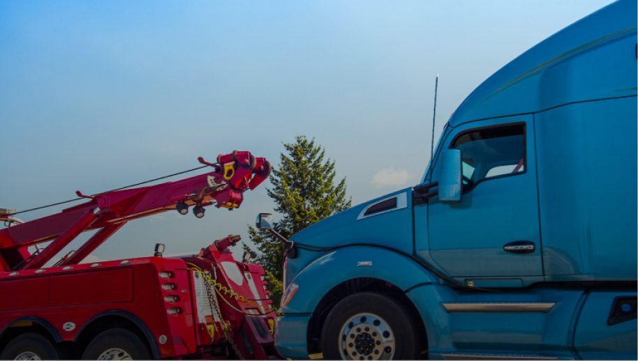Tow truck towing a blue semi-truck.