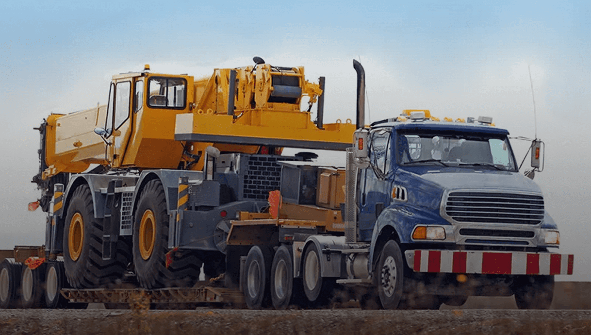 Heavy-duty crane loaded on a transport truck at a construction site.